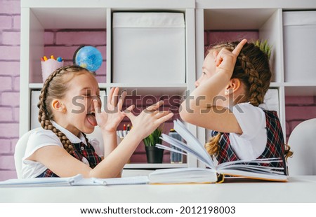 Two schoolgirls friends fool around during a lesson. Back to school concept. Royalty-Free Stock Photo #2012198003