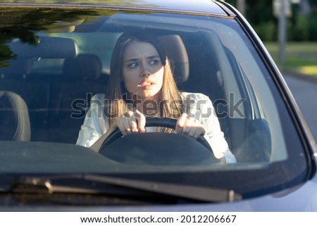 Woman drives her car for the first time, tries to avoid a car accident, is very nervous and scared, worries, clings tightly to the wheel. Inexperienced driver in stress and confusion after an accident Royalty-Free Stock Photo #2012206667