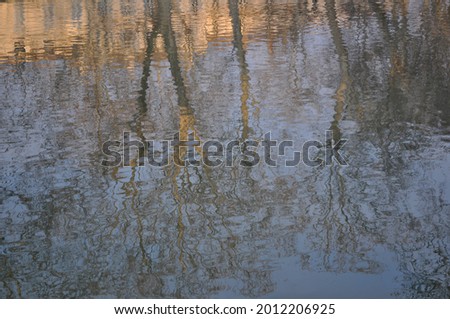 Winter landscape in the city of Nimes in Southern France, as reflected in the still water of a canal. Silhouettes of old buildings and bare trees as mirrored by the water. Can be used as background. Royalty-Free Stock Photo #2012206925