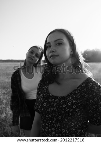 Two sisters walk in nature and communicate. They take pictures at sunset.