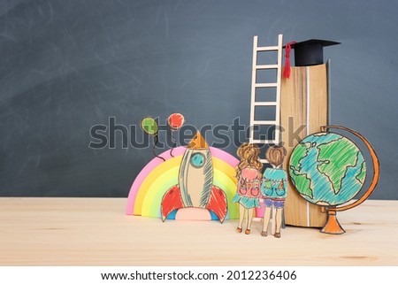 Back to school concept. Top view image of two kids standing next to ladder and book over wooden desk