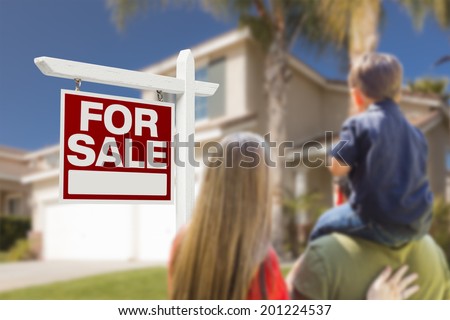 Curious Family Facing For Sale Real Estate Sign and Beautiful New House.