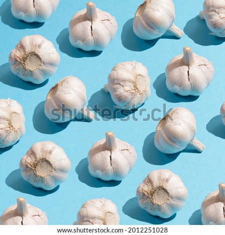 Photo pattern of garlic on a blue background Royalty-Free Stock Photo #2012251028