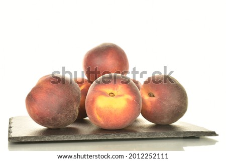 Several ripe organic peaches on a serving slate board, close-up, isolated on white.