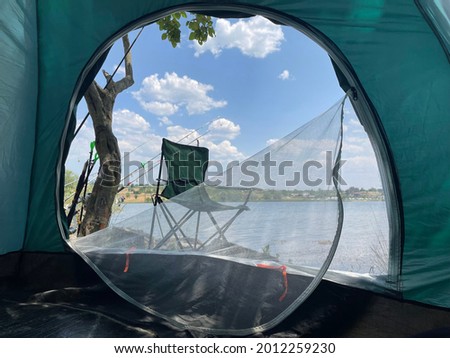 fishing rod, lake, camping chair and wonderful nature, camp photo taken from inside the tent