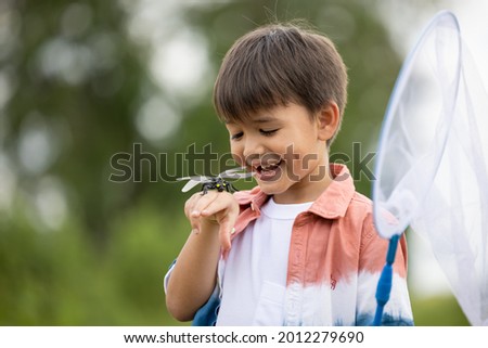 boy with dragonfly on holding hand in the nature background 