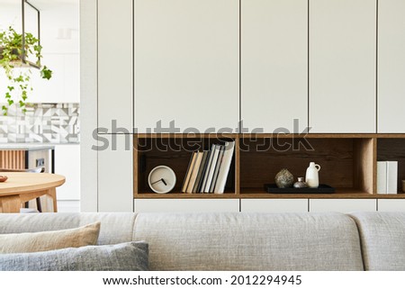 Stylish composition of creative living room interior details such as books, clocks and other personal accessories. White pannels. Kitchen on the background. Details. Template.