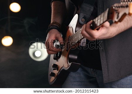 Man playing electric guitar on stage, closeup. Rock concert