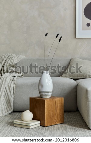Creative composition of stylish modern spacious living room with grey sofa, wooden cube, carpet, lamp, white design vases and small personal accesories. Creative wall and parquet floor. Details. 