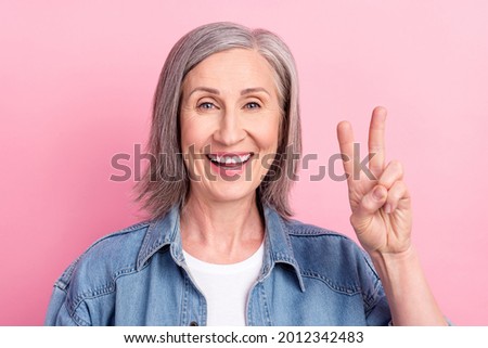 Photo of astonished aged lady show v-sign wear blue jacket isolated on pastel pink color background
