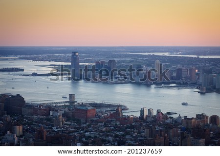 Aerial view of New York and Jersey City, spanning Chelsea, Hudson River and Ellis Island in New York,  and Liberty State Park in New Jersey. The evening light casts its  colors over the Hudson River.