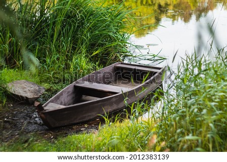 A wooden boat stands on the bank of the river near the reeds. Summer concept. Ukraine.