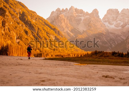 A majestic lake in the alpine mountains. Breathtaking views of the alps. A tourist is filming with a tripod. Travel photographer takes pictures of the mountain landscape.