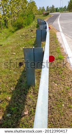 a fence that stretches on the side of the toll road as a protection from traffic accidents