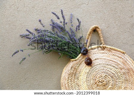 Straw bag, fresh lavender flowers and retro sunglasses, hanging on a concrete wall.