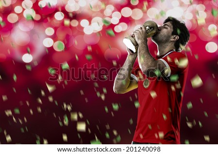 Swiss soccer player, celebrating the championship with a trophy in his hand. On a red lights background.