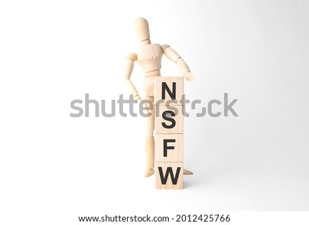 Wooden mannequin near tower of cubes with word nsfw on table against light background Royalty-Free Stock Photo #2012425766