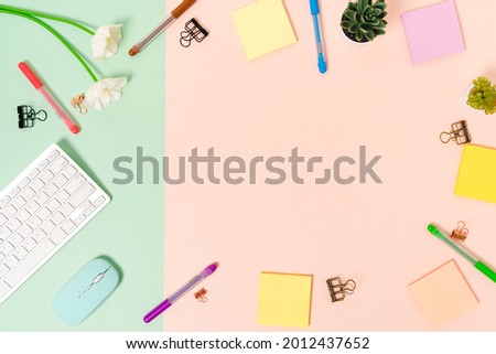 Minimal work space - Creative flat lay photo of workspace desk. Top view office desk with keyboard, mouse and adhesive note on pastel green pink color background. Top view with copy space photography.