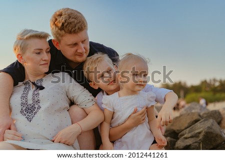 lovely caucasian family with mom expecting child enjoy sunset on beach. High quality photo