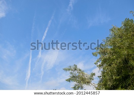Jet plane contrails or air vapor smoke type trails seen in clear light blue sky from home. Jet plane in sky