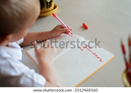 Happy left-handed boy writing in the paper book with his left hand, international left-hander day celebration, only lefties understand Royalty-Free Stock Photo #2012468360