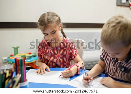 A lefty girl and righty boy writing at the same desk and nudge each other with elbows, international left-hander day celebration, only lefties understand Royalty-Free Stock Photo #2012469671