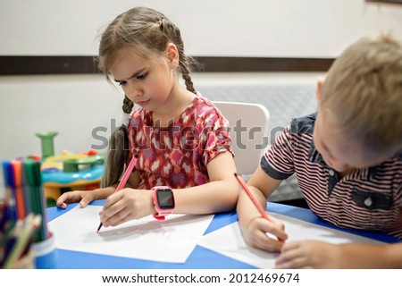 A lefty girl and righty boy writing at the same desk and nudge each other with elbows, international left-hander day celebration, only lefties understand Royalty-Free Stock Photo #2012469674