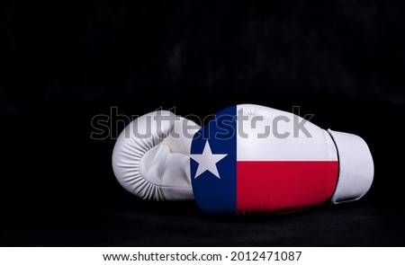 Boxing glove with Texas flag on black background.

