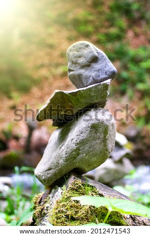 Rock pyramid, rock balancing art. Close-up of a stack of stones in perfect balance in a mountain forest. Sun rays. Meditation, balance, peace. Hobby. Vertical photo.