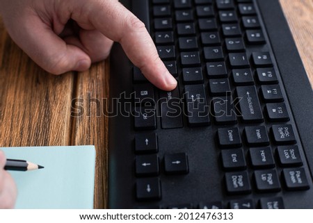 Hands Pressing Computer Keyboard Keys While Writing With Pencil In Notepad. Palms Typing Notebook Keypad And Writing Pencil Over Paper.