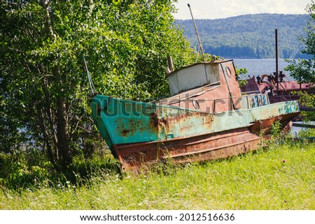 Rusty metal abandoned boat was left on the river shore