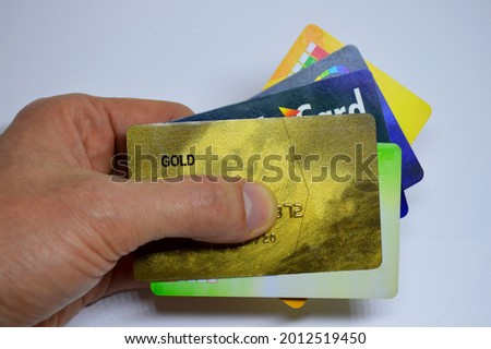 male hand holds five different plastic credit cards on white background