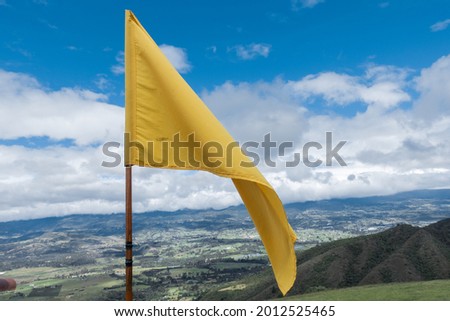Close up attention yellow flag on blue sky over a mountain
