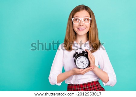 Portrait of attractive cheerful girl holding clock looking aside copy space isolated over bright teal turquoise color background