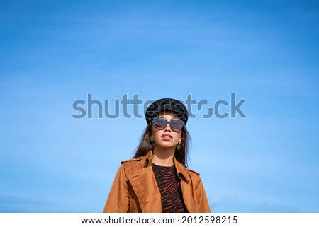 Female portrait of a young woman against a blue sky in sunglasses