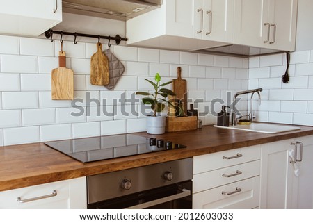 Kitchen brass utensils, chef accessories. Hanging kitchen with white tiles wall and wood tabletop.Green plant on kitchen background side view Royalty-Free Stock Photo #2012603033