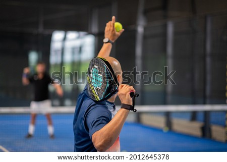 Monitor teaching padel class to man, his student - Trainer teaches boy how to play padel on indoor tennis court Royalty-Free Stock Photo #2012645378