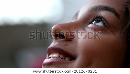 African descent girl looking up with HOPE and FAITH. Happy preteen child eye
