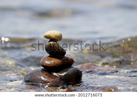 Tower of wet pebbles in the sea waves. Summer vacation, beach stones, balance and relax concept
