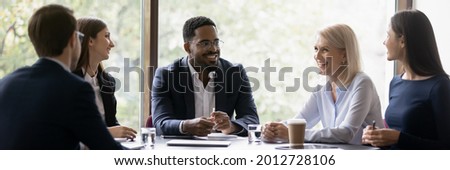 Happy diverse different aged business team discussing work. Leader and employees talking in office meeting room together, brainstorming, sharing ideas and solutions, negotiating on project. Royalty-Free Stock Photo #2012728106