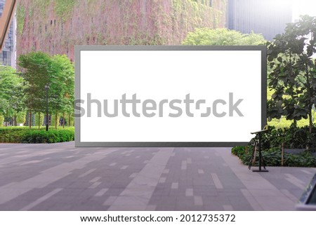 Blank advertising poster banner mockup in lush open air environment, empty exhibition space in foreground; large digital lightbox display screen. Billboard poster, out-of-home OOH media display space