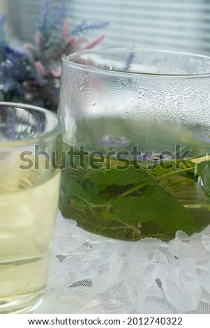 In a glass mug and teapot Fresh, floral, herbal tea made from mint and currant leaves in a mug.