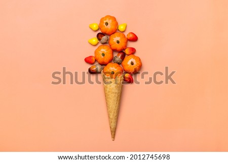 acorns, cones, pumpkins, berries in waffle cone for ice cream on orange background Top view Autumnal flat lay Holiday card