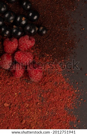 Fresh fruits and dried fruit powder. Currant and raspberries on dark paper background. Vegetarian healthy detox food.	