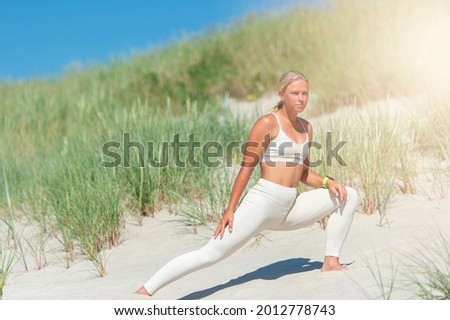 Woman practicing yoga on a sand dune on the beach