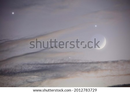 Young crescent Moon and stars on a twilight sky.