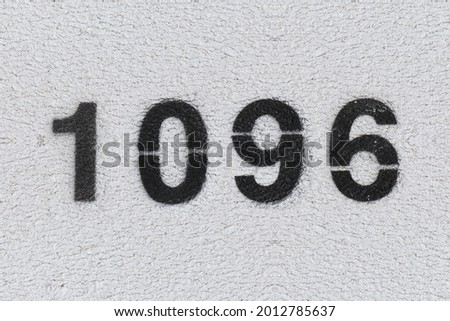 Black Number 1096 on the white wall. Spray paint. Number one thousand ninety six.