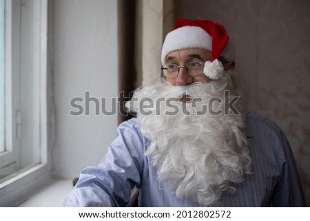 portrait of senior man in santa hat looking at camera