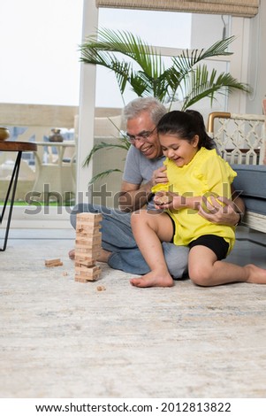 Grandfather enjoying with granddaughter wooden blocks at home