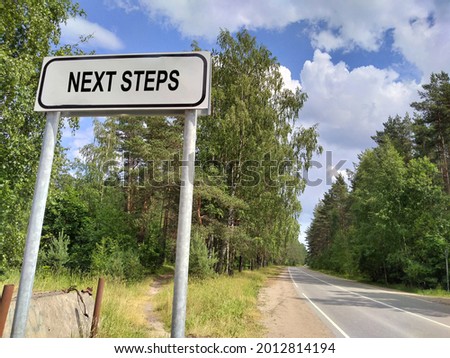 NEXT STEPS - text on the sign near the forest. The concept of moving forward